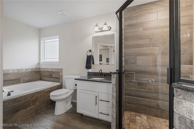 bathroom with a garden tub, vanity, toilet, a shower stall, and wood finished floors