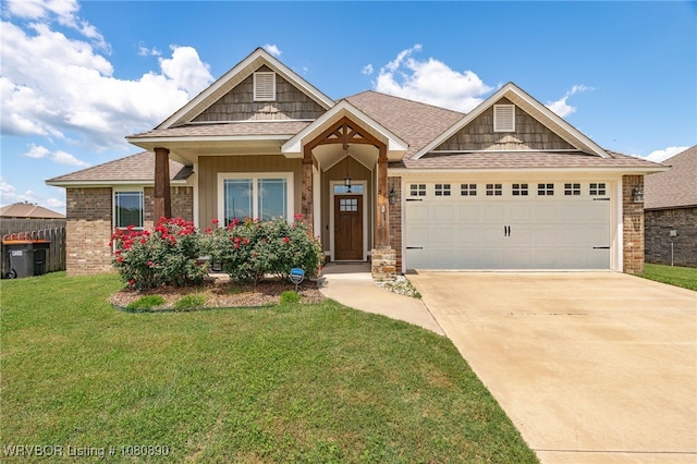 craftsman-style home featuring a front yard, driveway, an attached garage, and a shingled roof