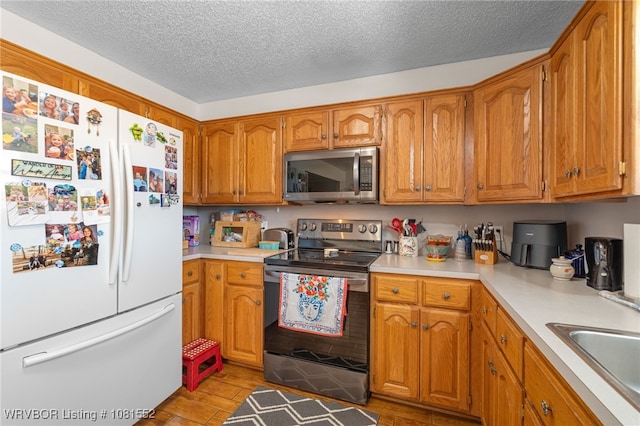 2027 High Meadow Ln, Alma, AR 72921 - kitchen featuring appliances with stainless steel finishes, brown cabinets, light countertops, a textured ceiling, and light wood finished floors