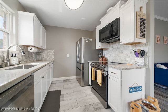 kitchen with appliances with stainless steel finishes, a sink, light stone counters, white cabinetry, and tasteful backsplash