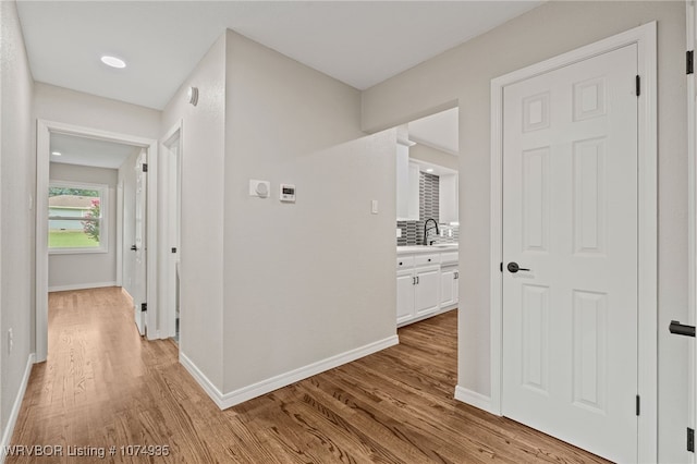 hall with light hardwood / wood-style floors and sink