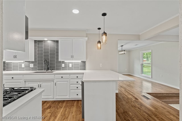 kitchen featuring sink, hanging light fixtures, ornamental molding, tasteful backsplash, and white cabinetry