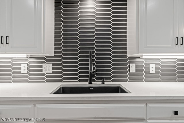 room details featuring decorative backsplash, white cabinets, and sink