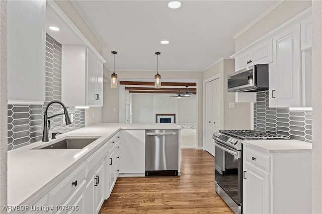 kitchen with kitchen peninsula, appliances with stainless steel finishes, white cabinetry, and sink