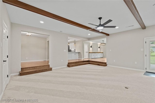 unfurnished living room featuring beamed ceiling, ceiling fan, and light colored carpet