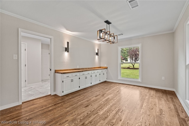 unfurnished dining area featuring light hardwood / wood-style floors, ornamental molding, and a notable chandelier