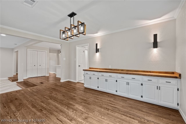 unfurnished dining area featuring hardwood / wood-style floors and crown molding