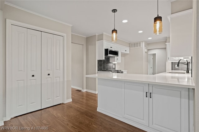 kitchen featuring pendant lighting, sink, kitchen peninsula, tasteful backsplash, and white cabinetry