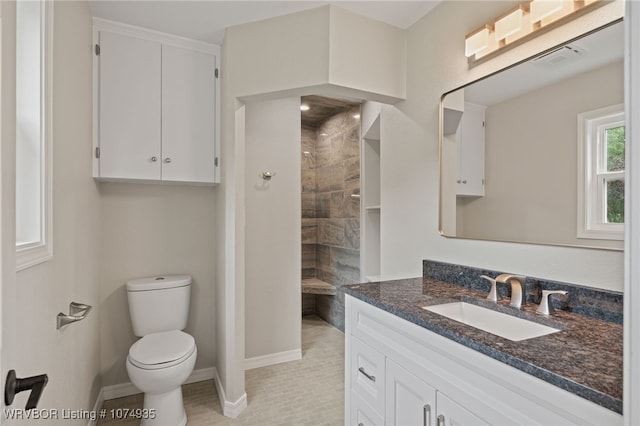 bathroom with tile patterned flooring, vanity, toilet, and tiled shower