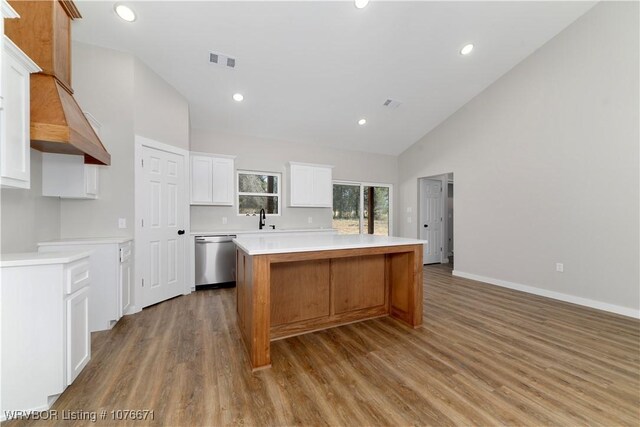 kitchen with dishwasher, a center island, high vaulted ceiling, sink, and white cabinetry