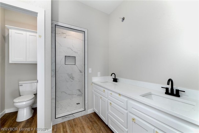 bathroom featuring tiled shower, vanity, wood-type flooring, and toilet