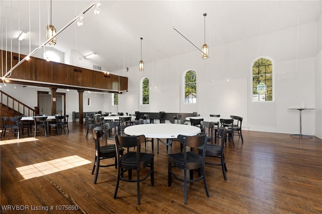 dining space with dark hardwood / wood-style floors and a towering ceiling