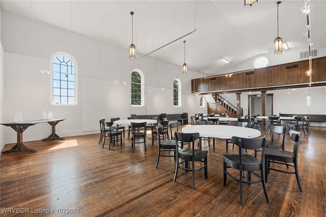 dining area with high vaulted ceiling and wood-type flooring