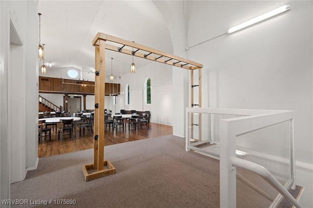 carpeted dining space with high vaulted ceiling