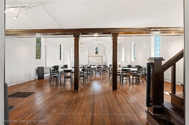 dining room featuring ornate columns, rail lighting, and dark hardwood / wood-style floors