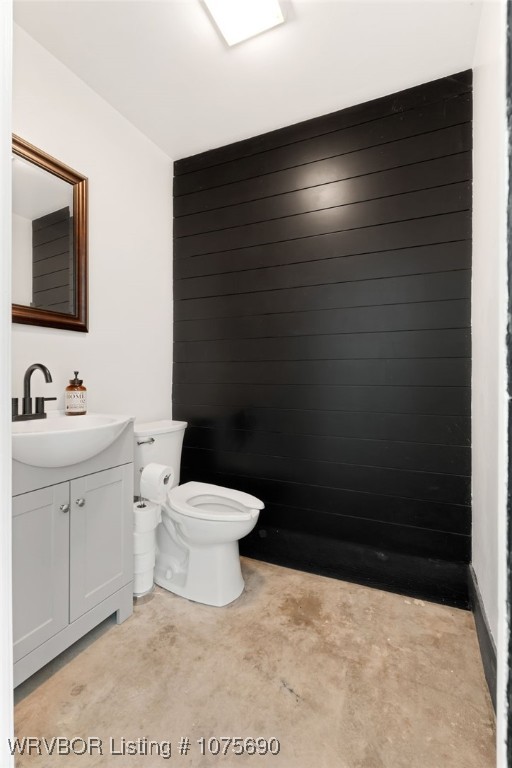 bathroom with concrete flooring, vanity, and toilet