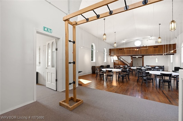 dining space with carpet flooring, plenty of natural light, and a towering ceiling