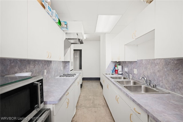 kitchen featuring decorative backsplash, gas stovetop, white cabinetry, and sink