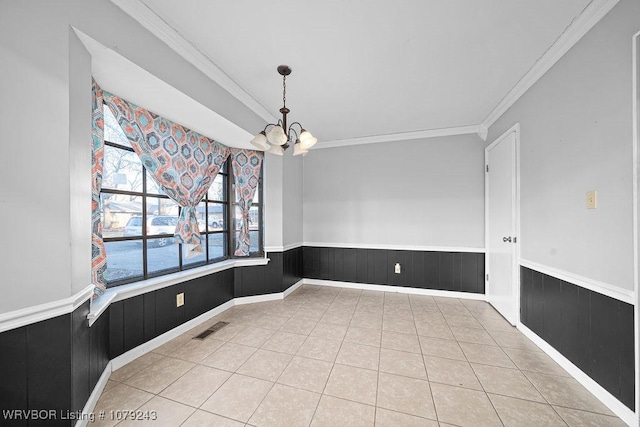 unfurnished dining area featuring light tile patterned floors, visible vents, a wainscoted wall, ornamental molding, and an inviting chandelier