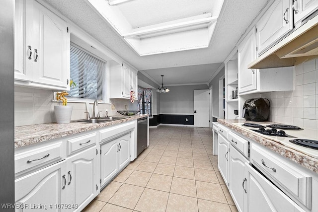 kitchen with light tile patterned floors, white electric cooktop, under cabinet range hood, white cabinetry, and stainless steel dishwasher