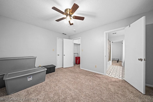 unfurnished bedroom featuring a textured ceiling, ceiling fan, carpet, and visible vents