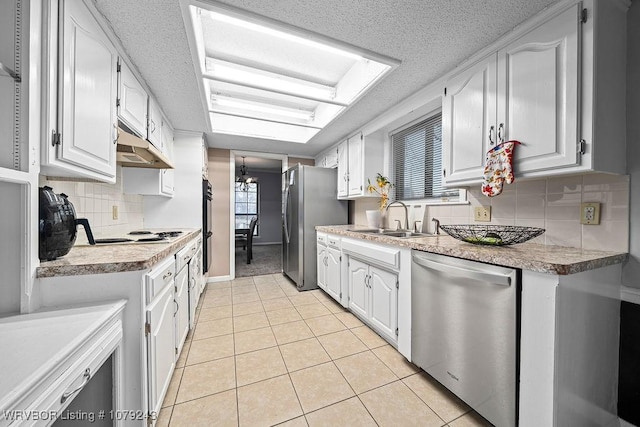 kitchen featuring light tile patterned floors, stainless steel appliances, under cabinet range hood, a chandelier, and a sink