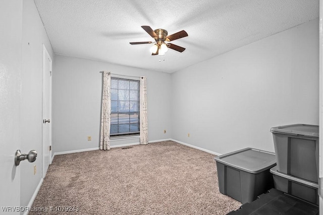 carpeted empty room with a ceiling fan, a textured ceiling, and baseboards