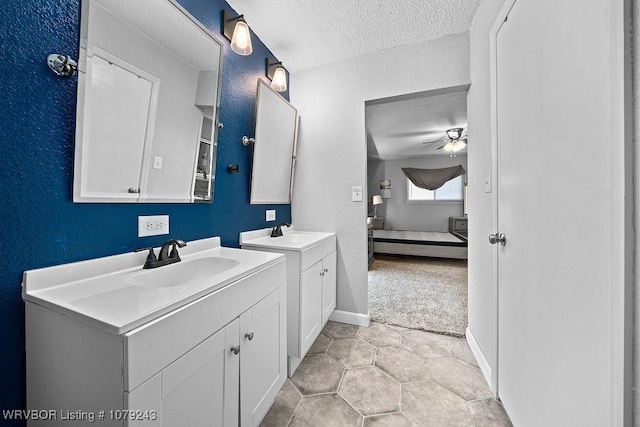 ensuite bathroom with two vanities, a sink, a textured ceiling, and ensuite bath