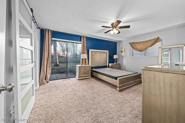 bedroom with a textured ceiling, access to outside, carpet flooring, and a ceiling fan