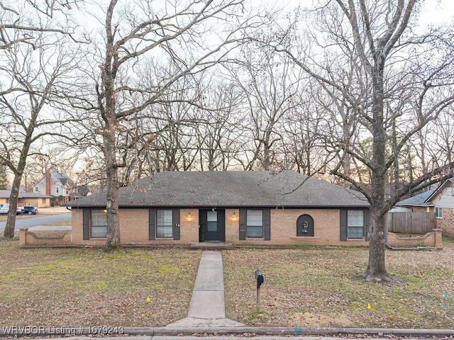 view of front of home with roof with shingles, a front yard, fence, and brick siding