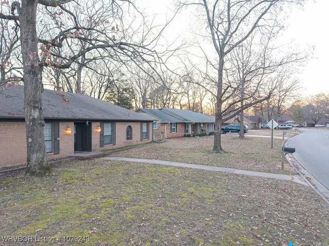 view of front of house with brick siding and roof with shingles