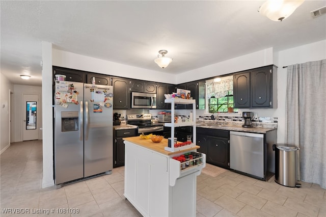 1424 Northwoods Dr, Alma, AR 72921 - kitchen featuring appliances with stainless steel finishes, light tile patterned floors, light countertops, and a center island