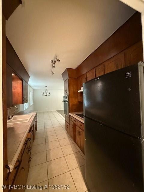 503 E Mayo Dr, Sallisaw, OK 74955 - kitchen featuring freestanding refrigerator, stainless steel oven, light tile patterned floors, light countertops, and brown cabinetry