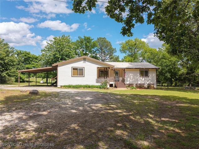 view of front of property featuring dirt driveway, an attached carport, covered porch, and a front lawn