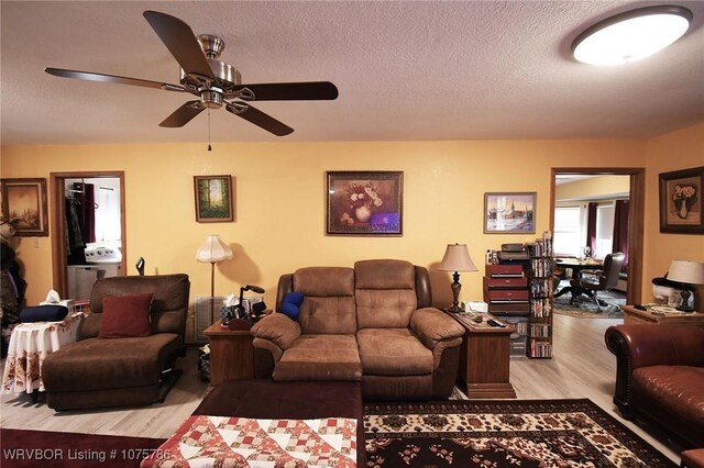 living room featuring ceiling fan, light hardwood / wood-style floors, and a textured ceiling