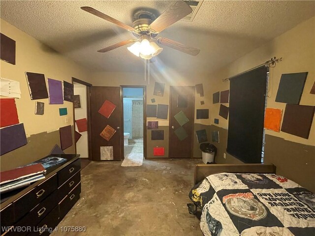 bedroom with ensuite bath, ceiling fan, concrete flooring, and a textured ceiling