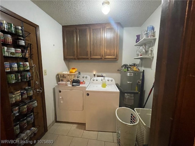 laundry area with cabinets, a textured ceiling, water heater, washing machine and clothes dryer, and light tile patterned flooring