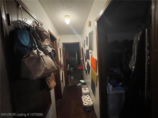 corridor with a textured ceiling and dark hardwood / wood-style flooring