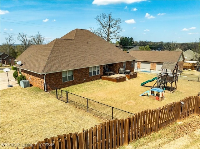 exterior space with central AC, a yard, a fenced backyard, and a playground
