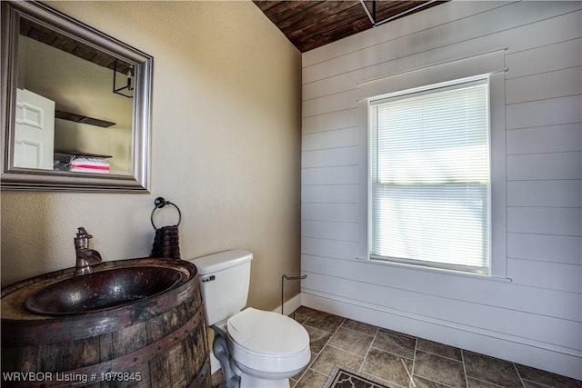 bathroom featuring wooden walls, toilet, wooden ceiling, and vanity