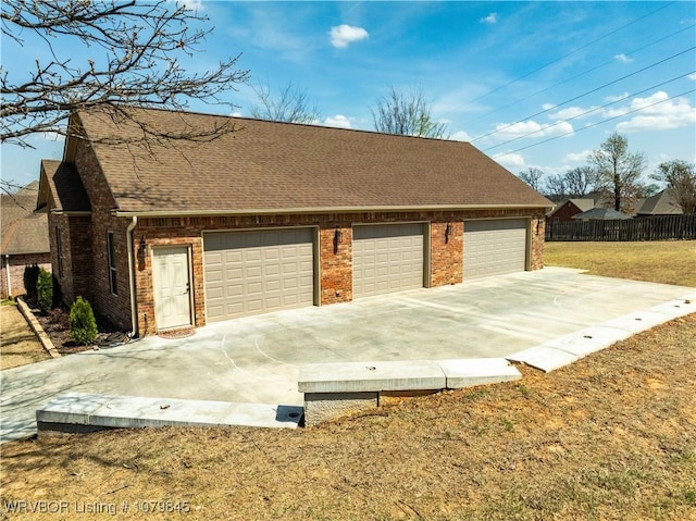 garage with concrete driveway and fence