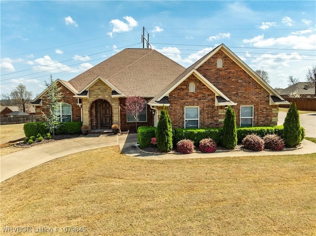 view of front facade with brick siding, fence, and a front lawn
