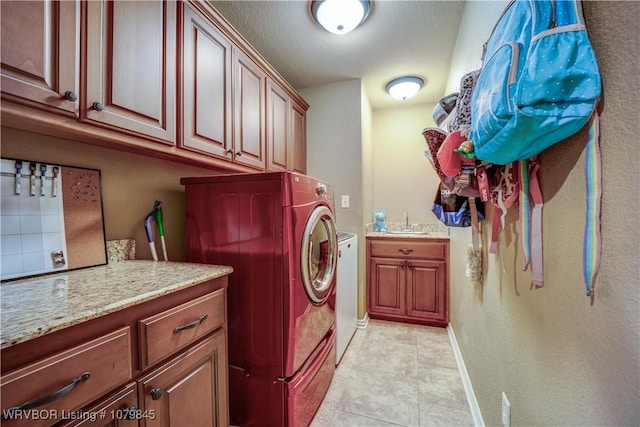 clothes washing area with light tile patterned floors, baseboards, a sink, cabinet space, and washing machine and dryer