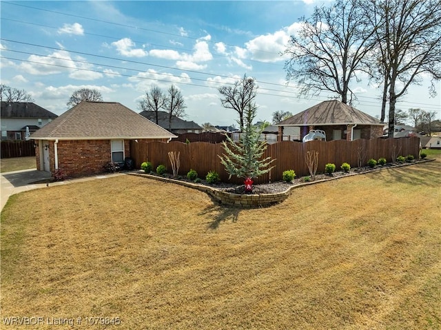 view of yard with driveway, a garage, and fence