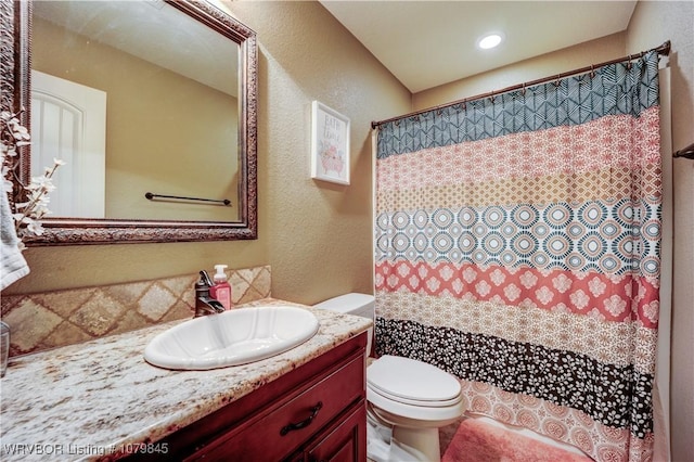 full bath with a textured wall, curtained shower, toilet, and vanity