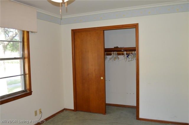 unfurnished bedroom with light colored carpet, crown molding, and a closet