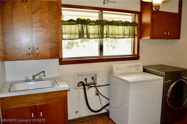 laundry area featuring separate washer and dryer, sink, cabinets, and wood-type flooring