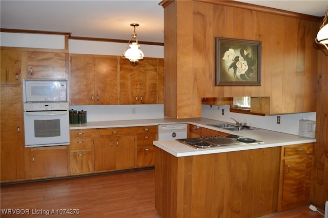 kitchen with kitchen peninsula, light wood-type flooring, white appliances, sink, and hanging light fixtures