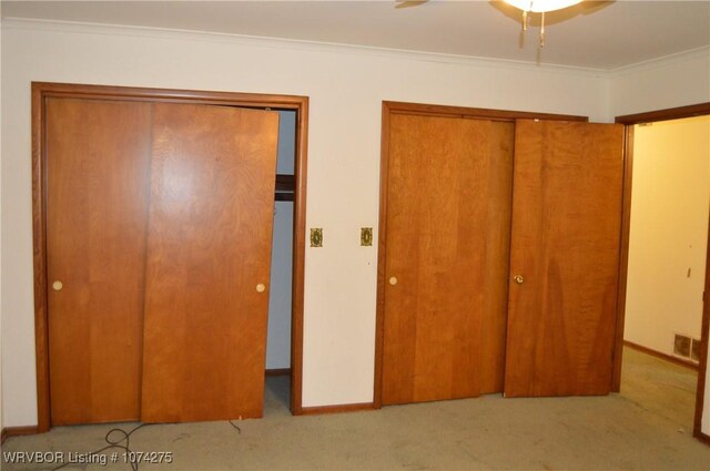 unfurnished bedroom with ceiling fan, light colored carpet, and crown molding