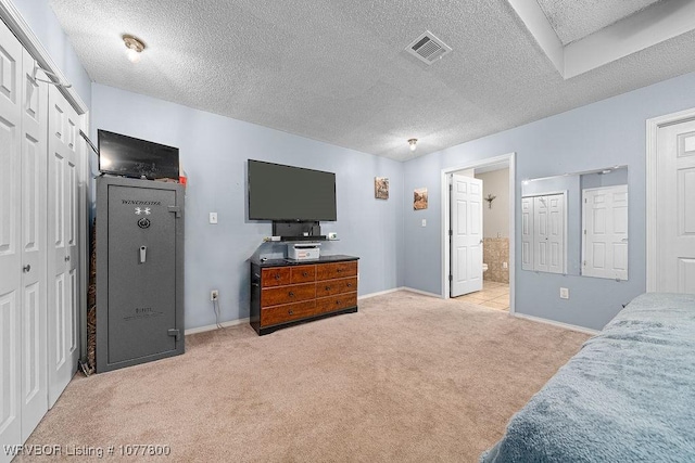 bedroom with connected bathroom, light carpet, and a textured ceiling